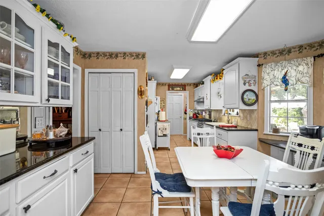 a kitchen with stainless steel appliances granite countertop a stove a refrigerator a dining table and chairs with wooden floor