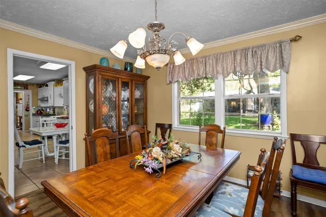 a view of a dining room with furniture a chandelier and large windows