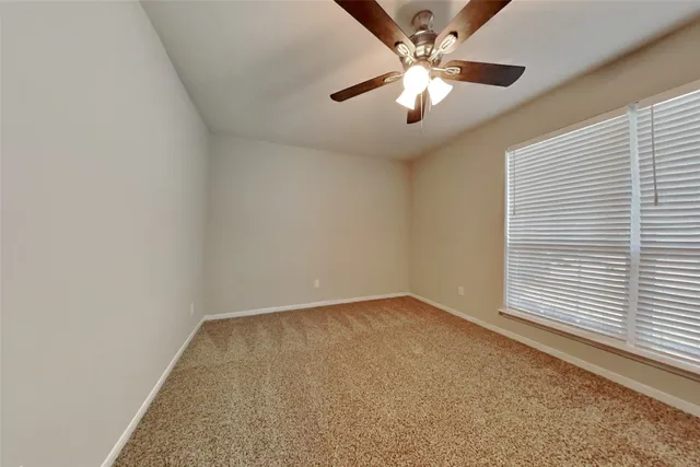 an empty room with a chandelier fan and windows