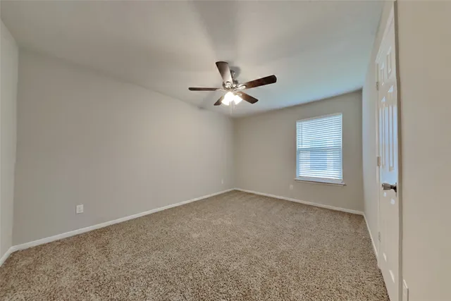 an empty room with a window and a ceiling fan