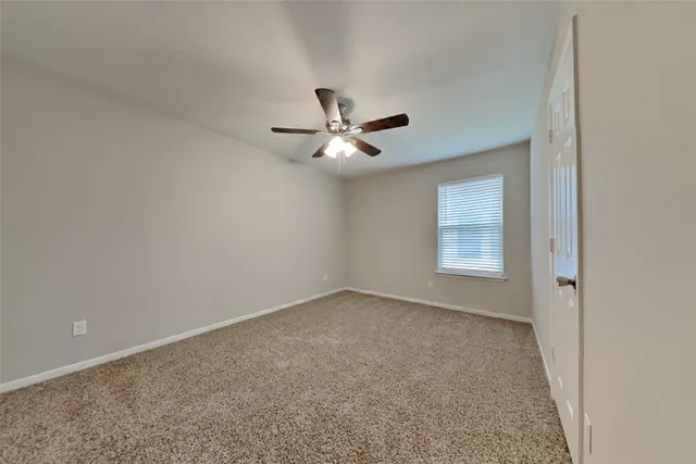 an empty room with a window and a ceiling fan
