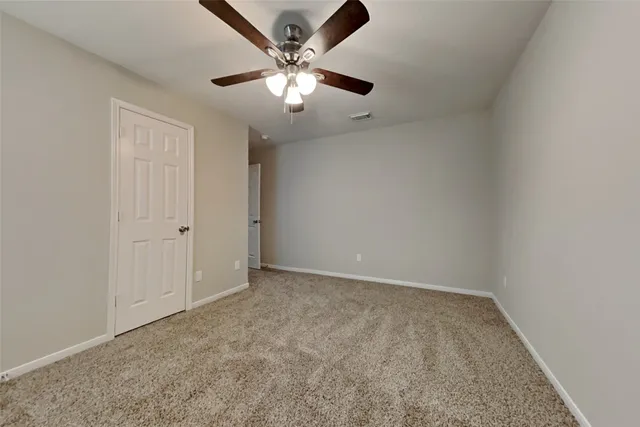 an empty room with a chandelier fan and windows