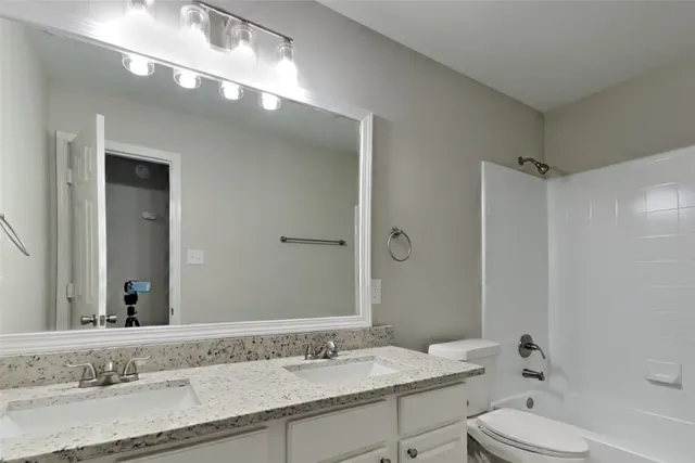a bathroom with a granite countertop sink a toilet and a mirror