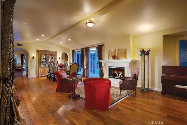 a living room with furniture a fireplace and a dining table with wooden floor