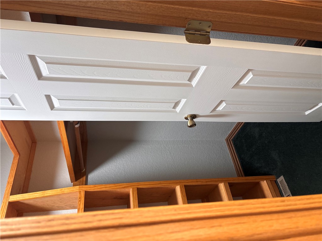 15262 Shipe Road Gravette, AR 72736 - Photo 39 of 60 White paneled door with brass hardware, wood-finish shelving, and built-in hanging rod