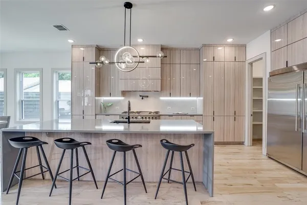 a kitchen with stainless steel appliances kitchen island granite countertop a dining table chairs and white cabinets