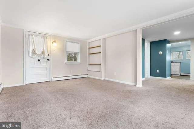 a view of an empty room with closet and a window