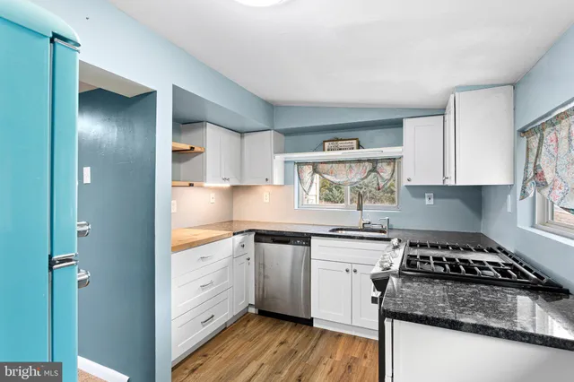a kitchen with cabinets appliances wooden floor and a window