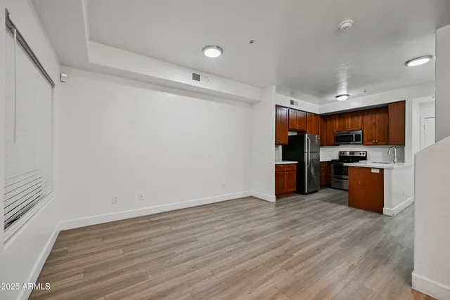 a view of kitchen with stainless steel appliances wooden floor and large window