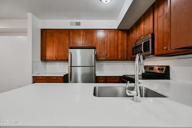 a kitchen with stainless steel appliances granite countertop a refrigerator a stove a sink and dishwasher