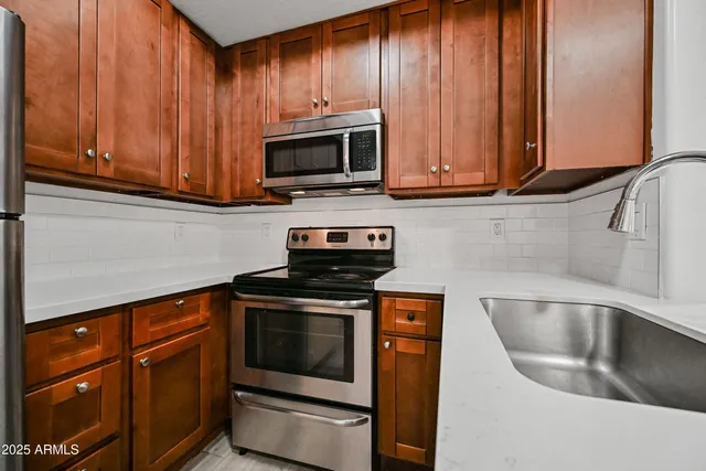 a kitchen with stainless steel appliances granite countertop wooden cabinets a stove and a sink