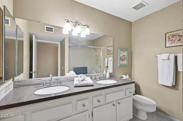 a bathroom with a granite countertop sink and a mirror with toilet