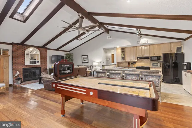 a living room with stainless steel appliances furniture a rug and a kitchen view