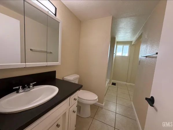 a bathroom with a granite countertop sink a toilet and a mirror