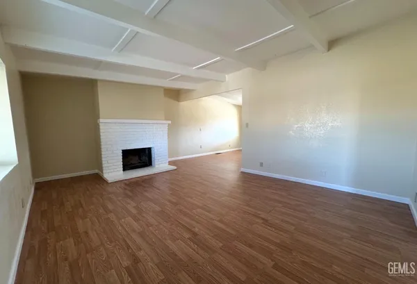 a view of empty room with wooden floor and fireplace