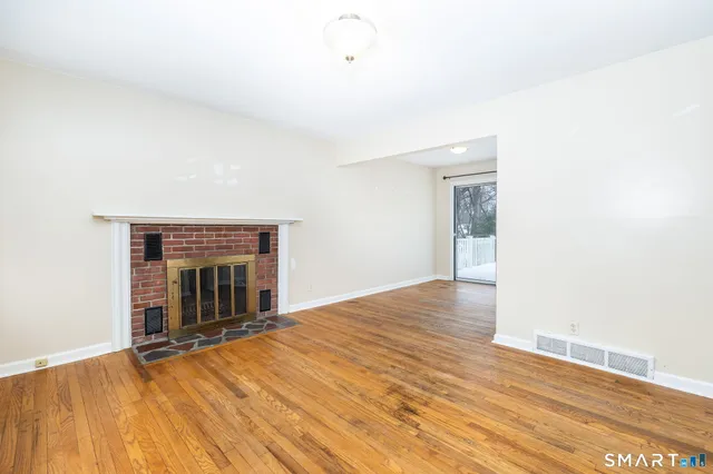 a view of empty room with wooden floor and fireplace