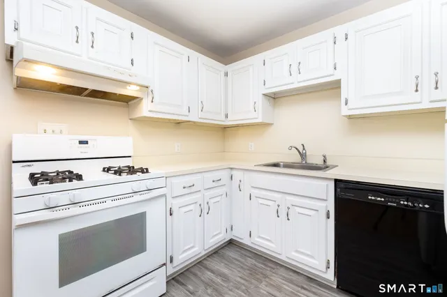 a kitchen with granite countertop white cabinets and white appliances