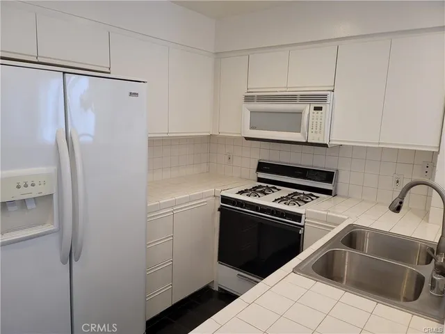 a kitchen with white cabinets and white appliances