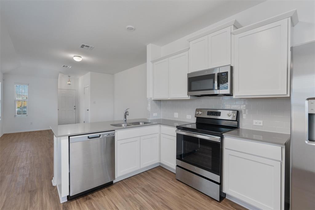 108 Joe Kidd Lane Jarrell, TX 76537 - Photo 13 of 22 a kitchen with stainless steel appliances granite countertop a stove top oven a sink and white cabinets