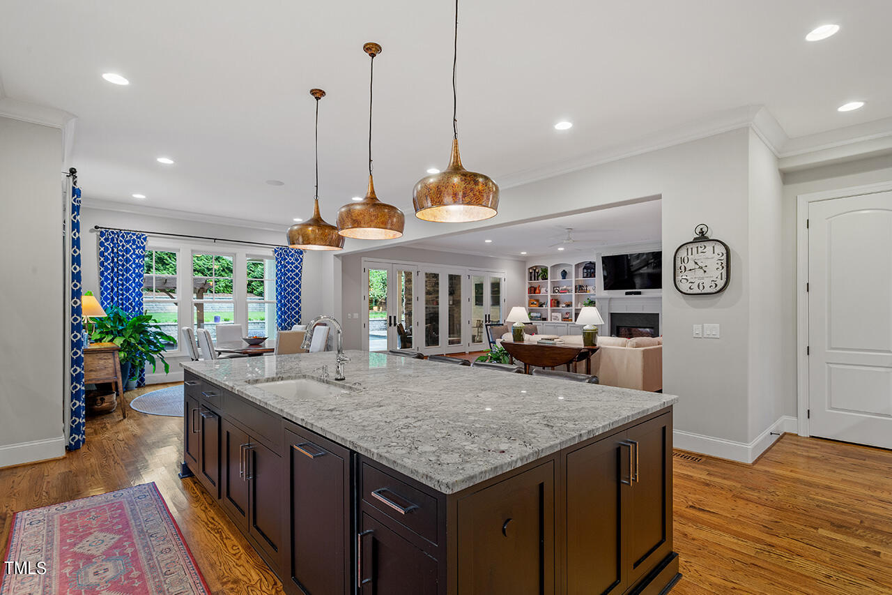 2311 Churchill Road Raleigh, NC 27608 - Photo 29 of 73 a kitchen with kitchen island granite countertop a stove a sink a oven and a dining table with wooden floor