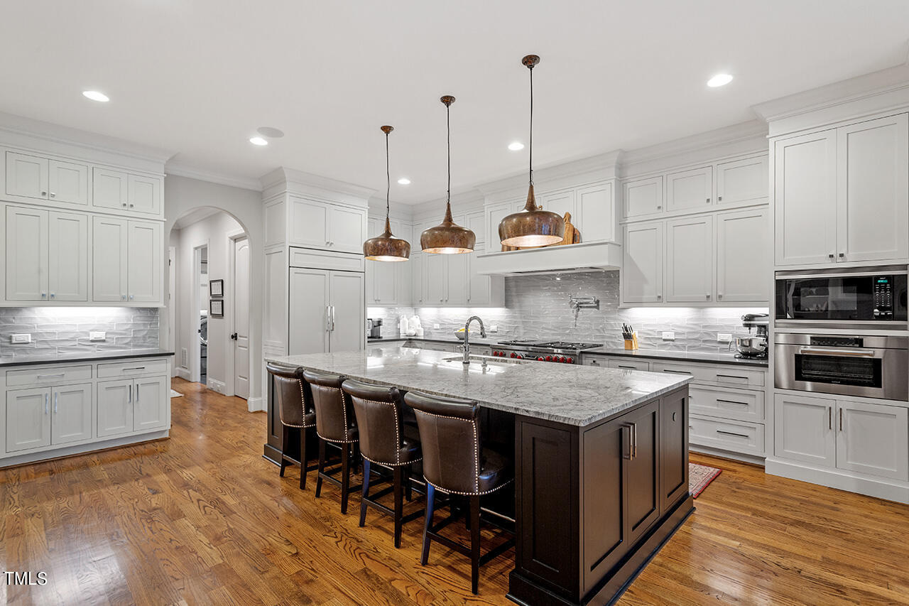 2311 Churchill Road Raleigh, NC 27608 - Photo 32 of 73 a kitchen with stainless steel appliances granite countertop a stove a sink dishwasher a refrigerator and a dining table with wooden floor