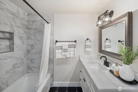 a bathroom with a double vanity sink a mirror and a bathtub