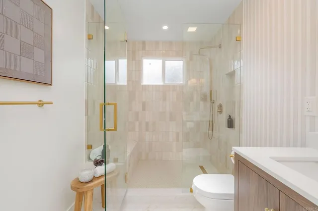a bathroom with a granite countertop sink a toilet and shower