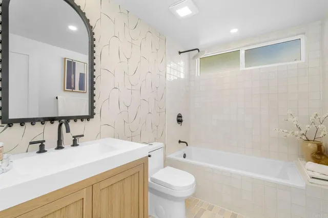 a bathroom with a bathtub shower sink vanity mirror and toilet