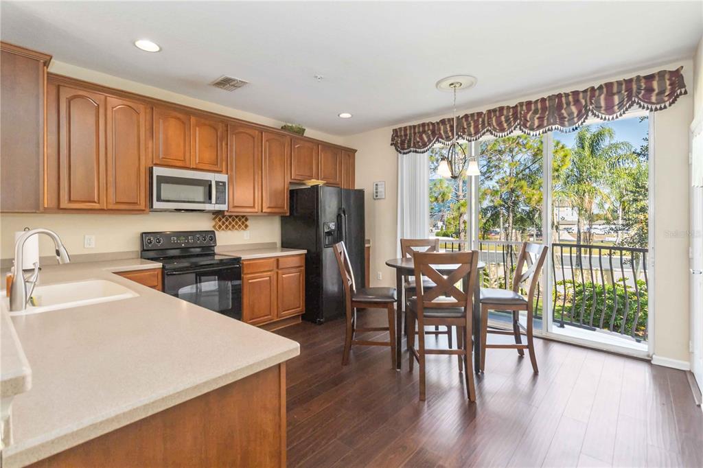 5038 Tideview Circle, Unit 26 Orlando, FL 32819 - Photo 8 of 42 a kitchen with stainless steel appliances granite countertop a stove a refrigerator a sink dishwasher with a dining table and chairs with wooden floor