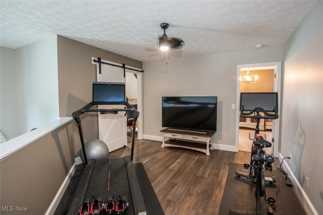 632 Rundle Street Lagrange, OH 44050 - Photo 19 of 30 Exercise area with dark wood-style flooring, a textured ceiling, a barn door, and ceiling fan