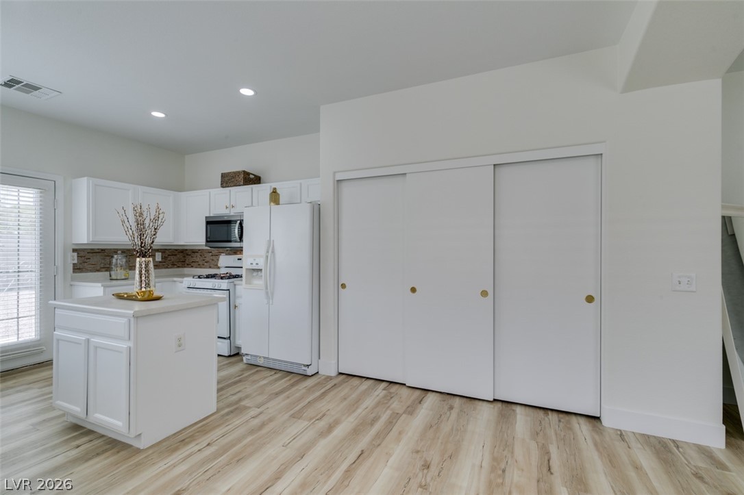 10959 Pumpkin Ridge Avenue Las Vegas, NV 89135 - Photo 11 of 51 A clean, modern kitchen area boast light wood-look flooring. Stainless steel and white appliances offering a fresh aesthetic.
