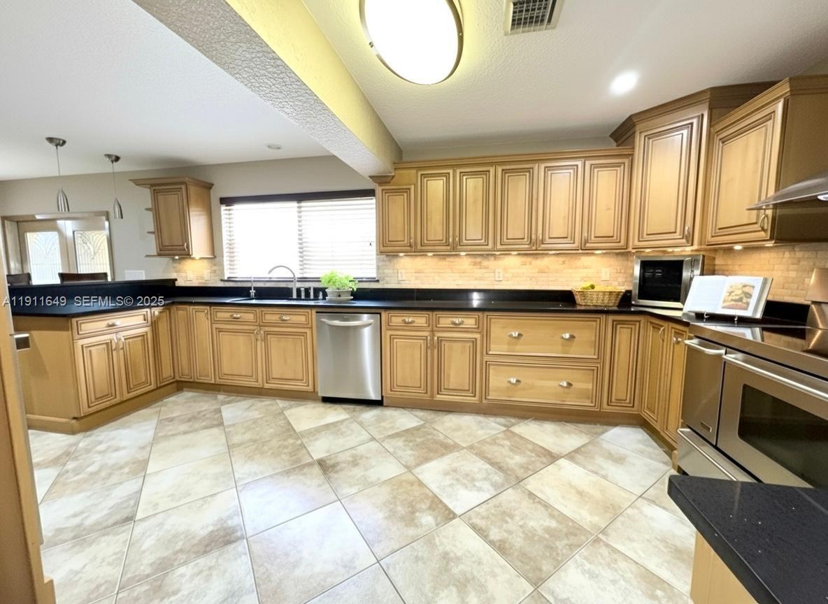 6905 Southwest 148th Court Miami, FL 33193 - Photo 18 of 26 a large kitchen with granite countertop a stove sink and cabinets