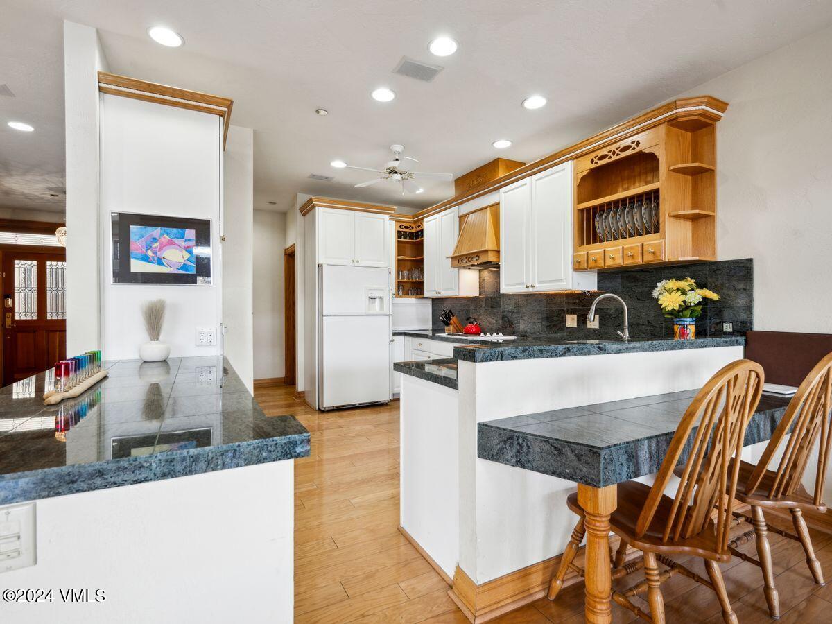 137 Main Street, Unit R203 Edwards, CO 81632 - Photo 5 of 39 a kitchen with stainless steel appliances granite countertop a refrigerator a stove a sink and white cabinets with wooden floor
