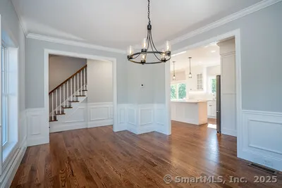 a view of a hallway with wooden floor and a chandelier
