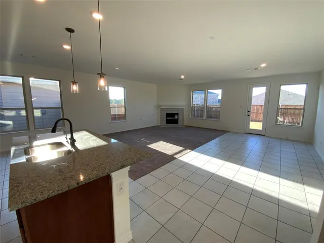 a view of a kitchen with kitchen island a sink wooden floor and a large window
