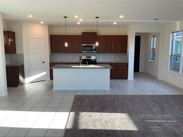 a large kitchen with stainless steel appliances kitchen island granite countertop a large counter top a stove a sink and a refrigerator