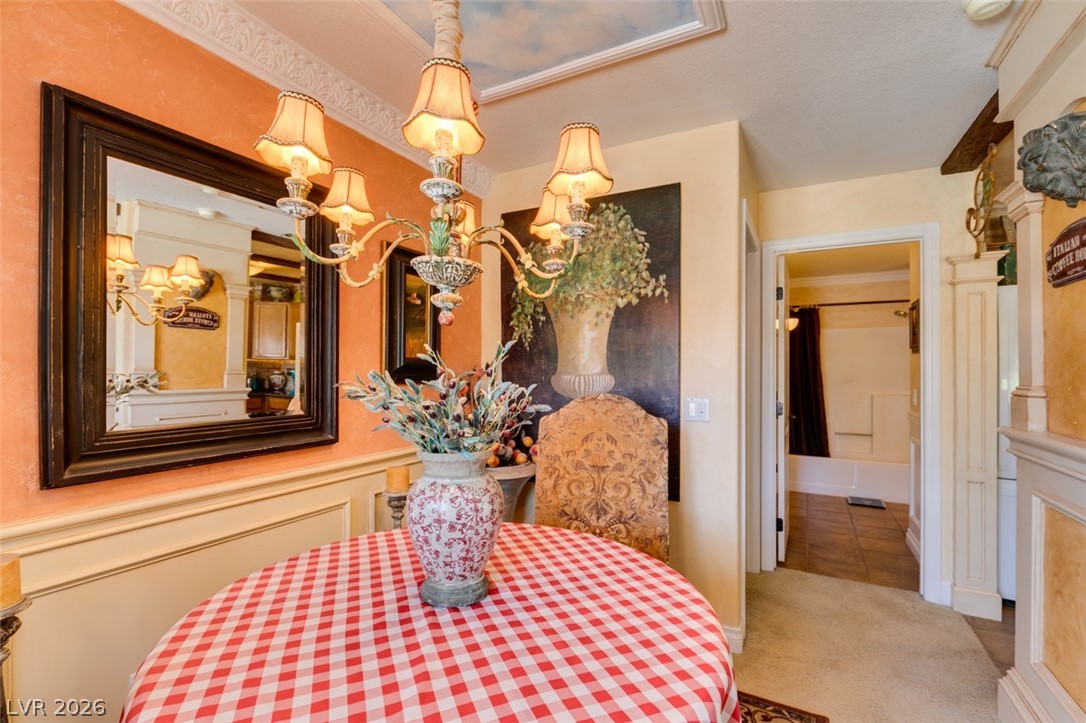 9325 West Desert Inn Road, Unit 244 Las Vegas, NV 89117 - Photo 15 of 55 A charming dining space boasts a striking chandelier and ornate ceiling molding, offering a cozy spot for meals.
