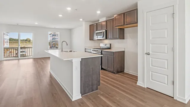 a kitchen with stainless steel appliances granite countertop a refrigerator a stove top oven a sink and dishwasher with wooden floor