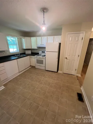 a large white kitchen with a sink a microwave and a refrigerator