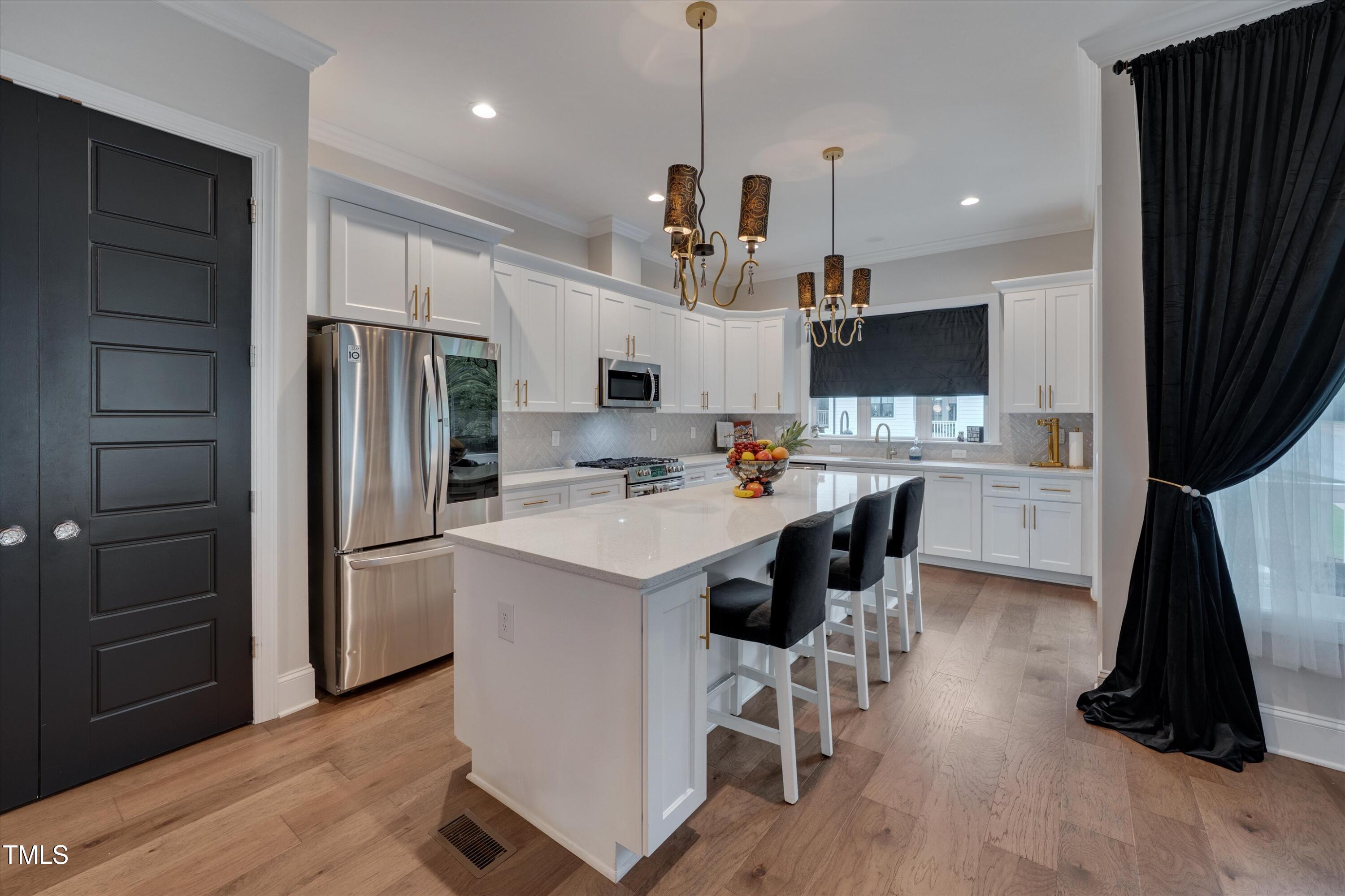 4902 Trek Lane Raleigh, NC 27606 - Photo 3 of 25 a kitchen with kitchen island white cabinets and stainless steel appliances