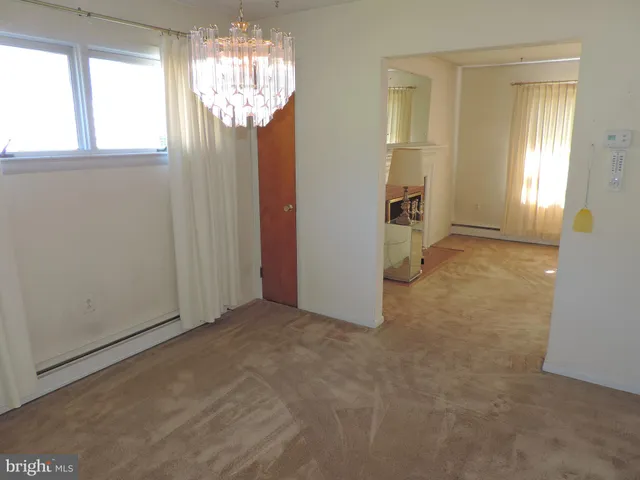 an empty room that has a large window and chandelier