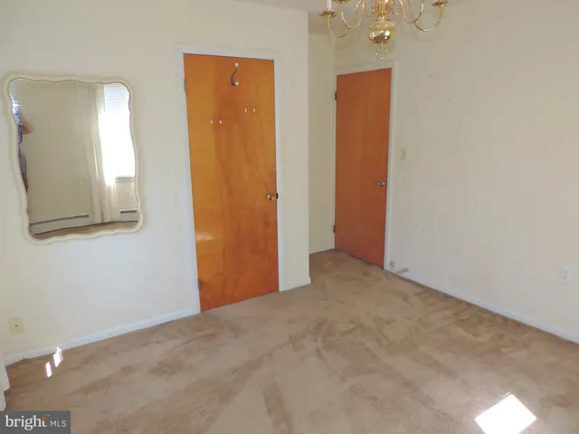 an empty room with mirror and a bathroom