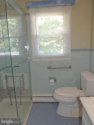 a white toilet sitting next to a window in a bathroom
