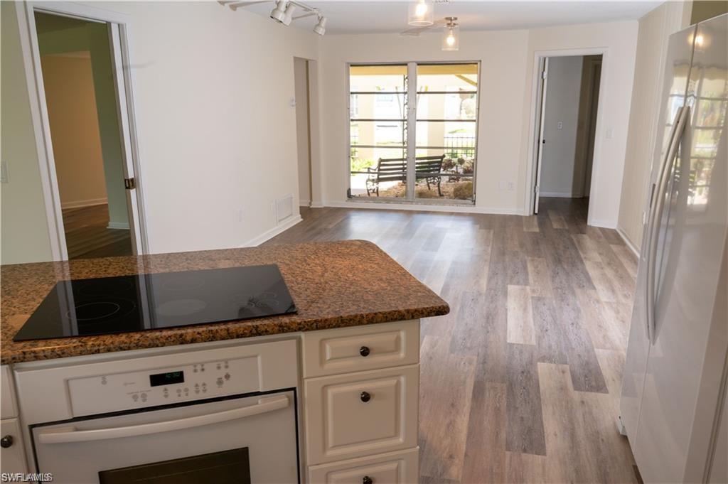 5654 Eichen Circle Fort Myers, FL 33919 - Photo 47 of 47 Kitchen with white appliances, white cabinets, dark stone countertops, light wood-type flooring, and open floor plan
