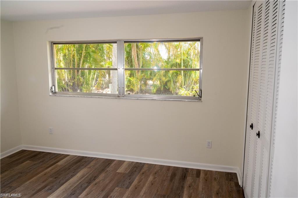 5654 Eichen Circle Fort Myers, FL 33919 - Photo 34 of 47 Unfurnished bedroom featuring multiple windows, dark wood-style floors, and a closet