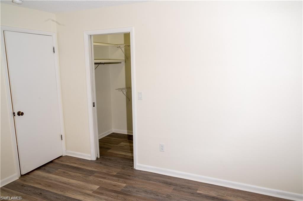 5654 Eichen Circle Fort Myers, FL 33919 - Photo 38 of 47 Unfurnished bedroom featuring dark wood-style flooring and a walk in closet