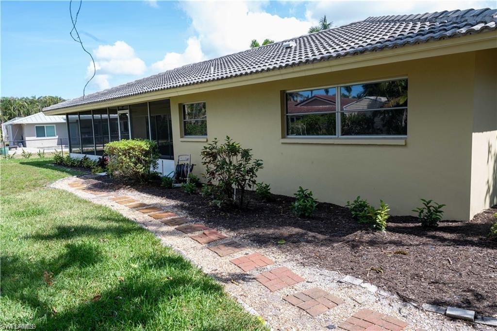 5654 Eichen Circle Fort Myers, FL 33919 - Photo 4 of 47 View of property exterior featuring stucco siding, a sunroom, a lawn, and a tile roof
