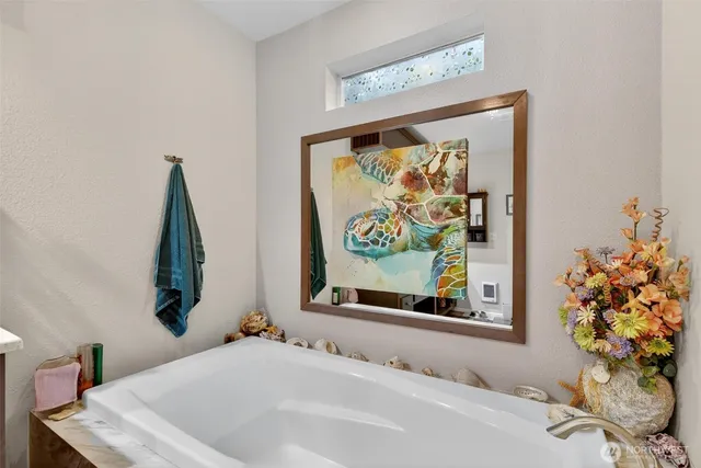 a white bath tub sitting next to a white toilet and vanity