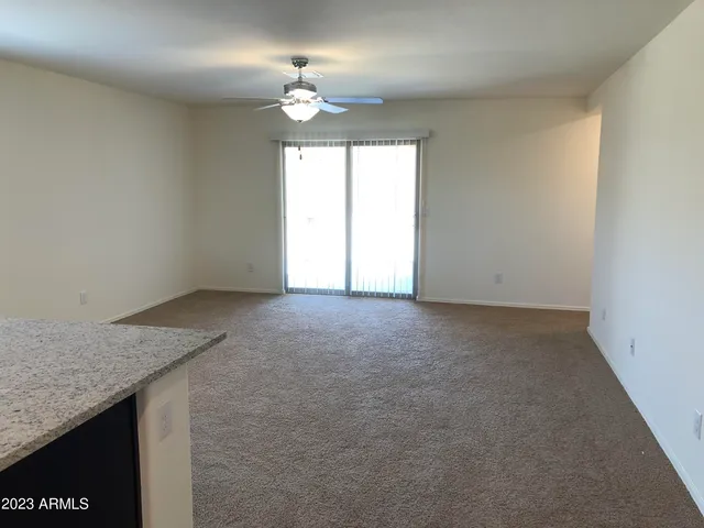 an empty room with a chandelier fan and windows