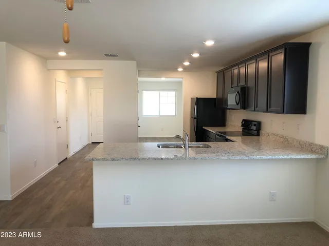 a view of a kitchen with kitchen island a sink stainless steel appliances and cabinets